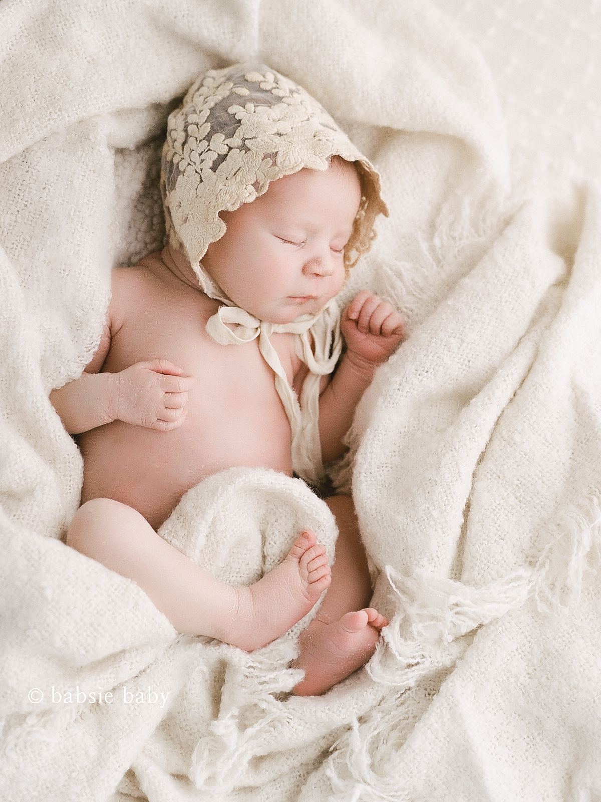 Sleeping baby girl wearing a lace ivory bonnet.